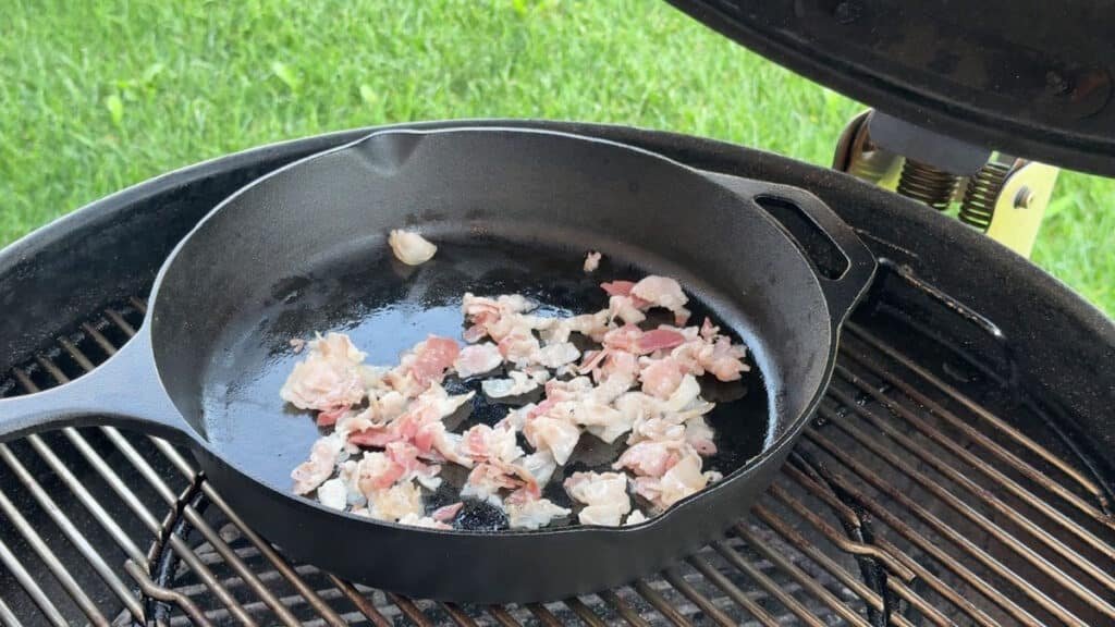 Padella in ghisa su barbecue a carbone per rosolatura bacon