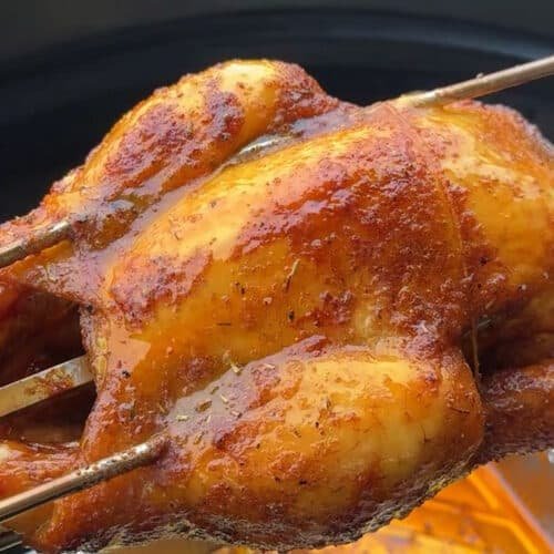 Pollo al girarrosto succoso e dorato che cuoce lentamente sul barbecue