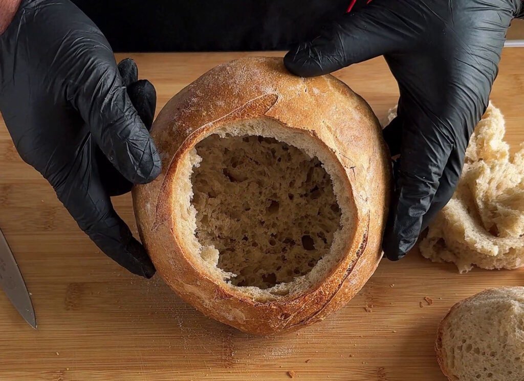 Pagnotta di pane casereccio svuotata per la preparazione della ricetta della pagnotta ripiena.