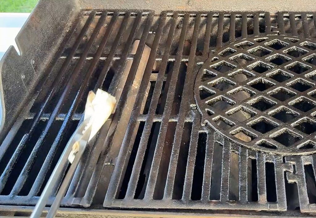 Pinza da barbecue che tiene un tampone di carta imbevuto d'olio per lubrificare le griglie di ghisa prima della cottura.