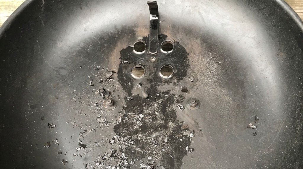 grasso vaporizzato che si è condensato e carbonizzato all'interno del coperchio del barbecue (non è vernice)