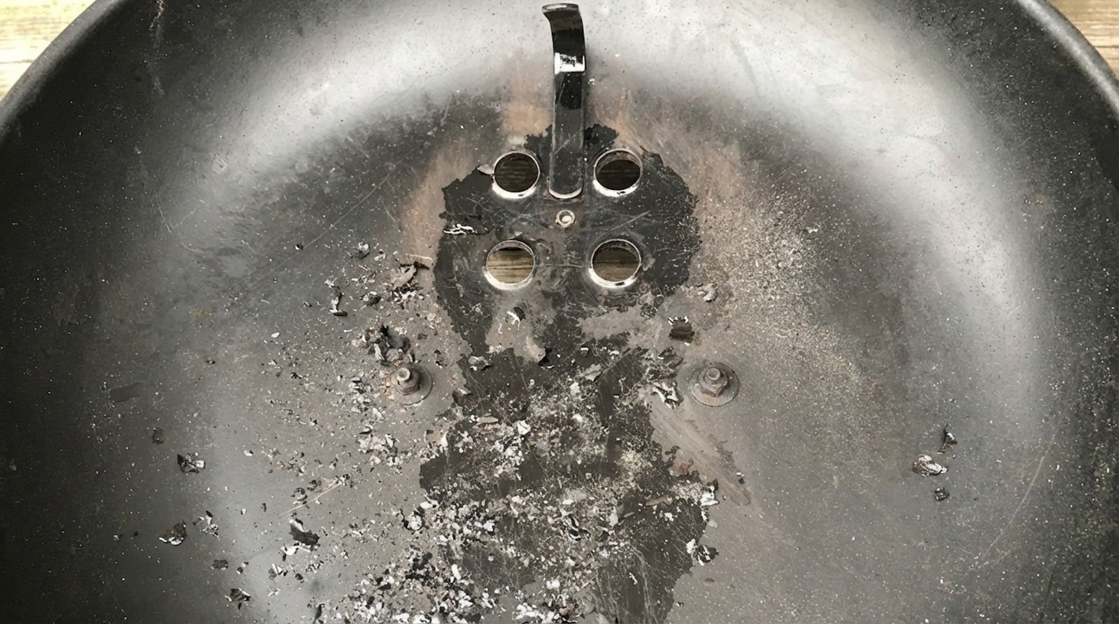 grasso vaporizzato che si è condensato e carbonizzato all'interno del coperchio del barbecue (non è vernice)