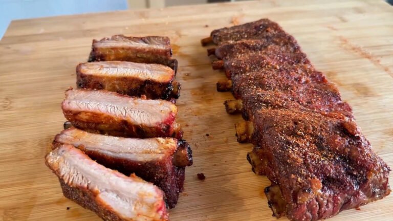 Costine al barbecue a gas tagliate sul tagliere in legno, con il bark speziato croccante e la carne interna succosa