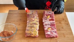 Stesura di un velo di senape classica sulle costine crude da usare come legante per far aderire il rub